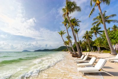 Sunbeds under tropical palms on beautiful Bai Sao beach in Vietn